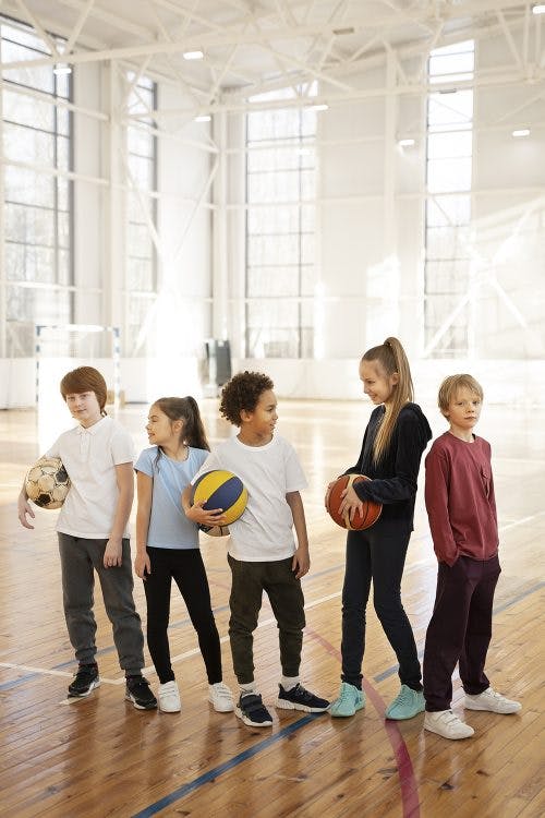 full-shot-children-holding-balls-gym